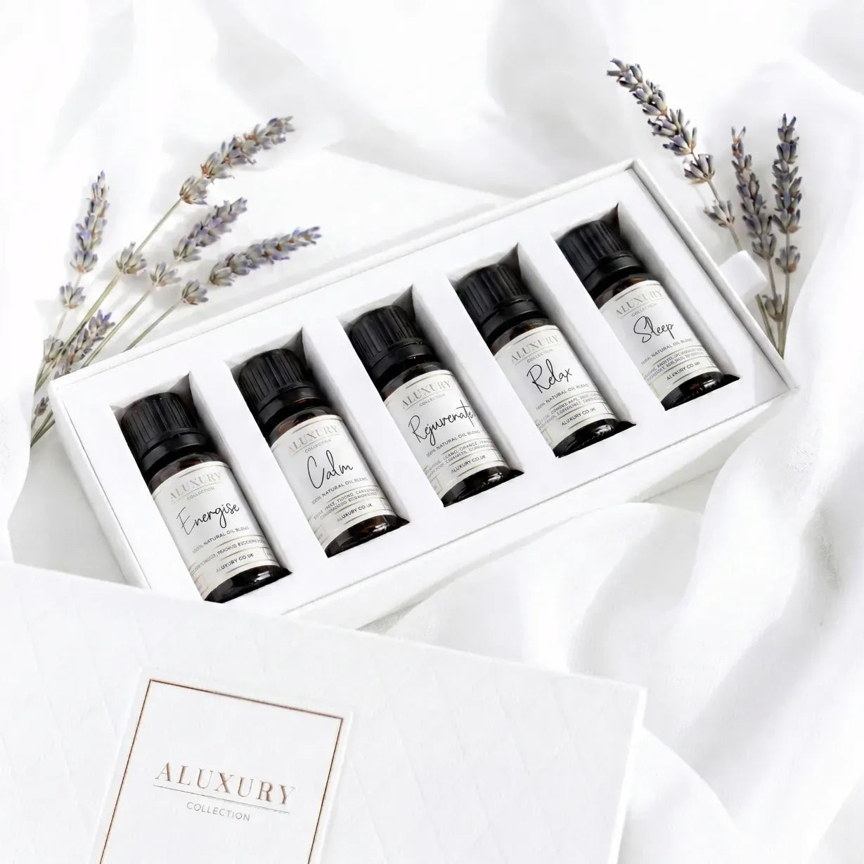 Set of six essential oil blends with a white box, surrounded by lavender flowers on a white background.