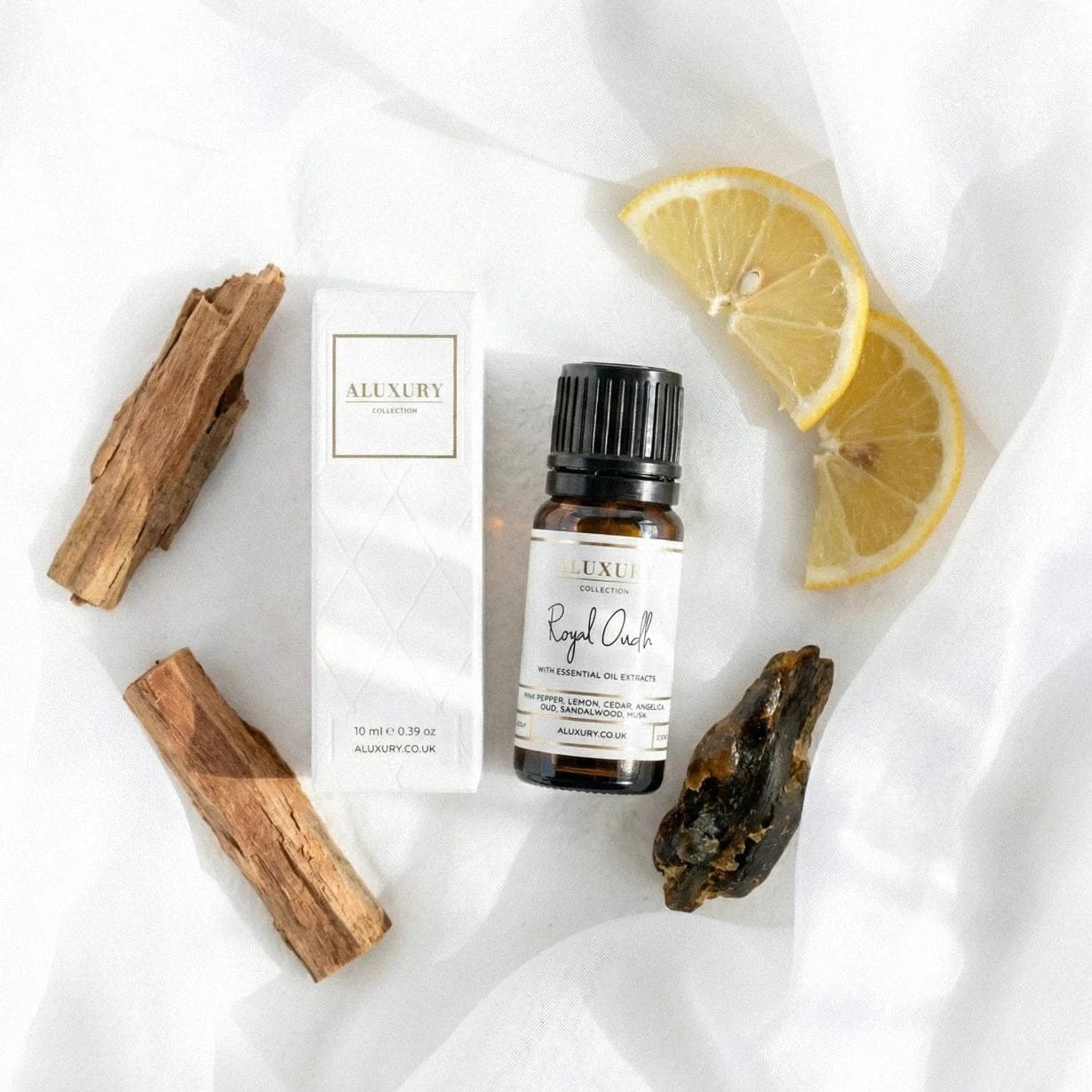 Aluxury Royal Oudh essential oil blend bottle and packaging on a white fabric background