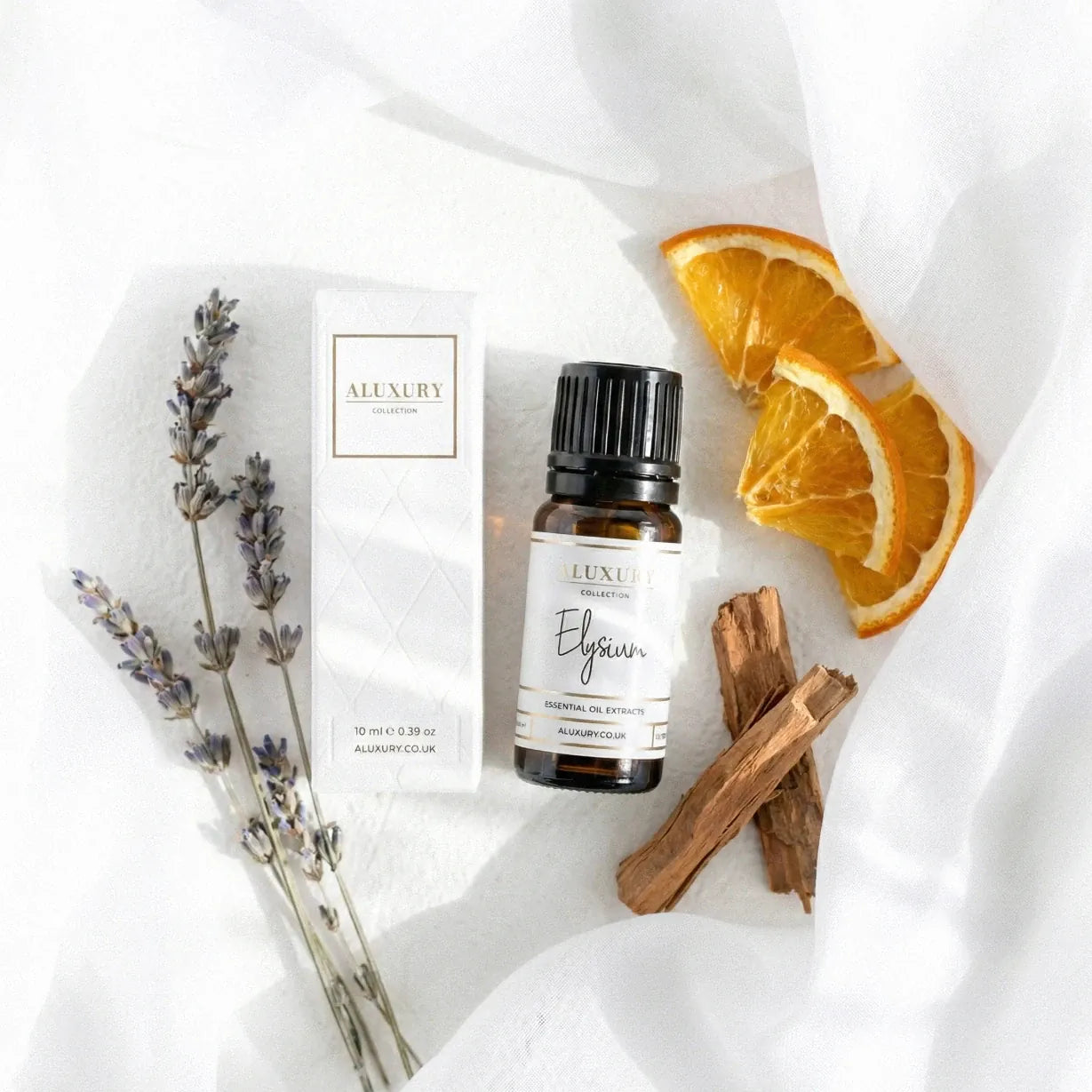 Aluxury essential oil bottle with packaging, lavender, orange slices, and sandalwood sticks on a white background