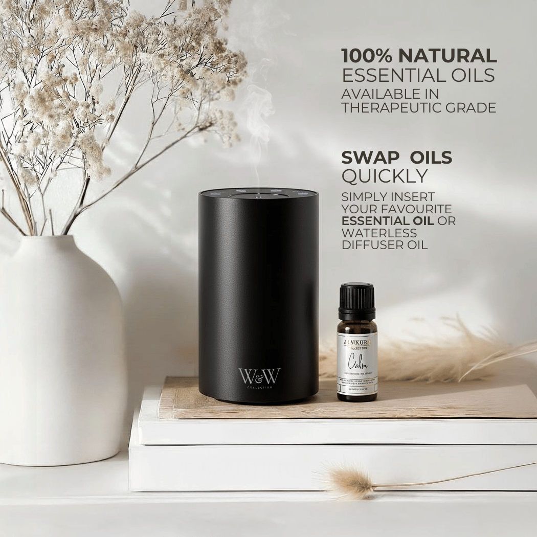 Black waterless diffuser and essential oil bottle on a wooden surface with decorative elements.
