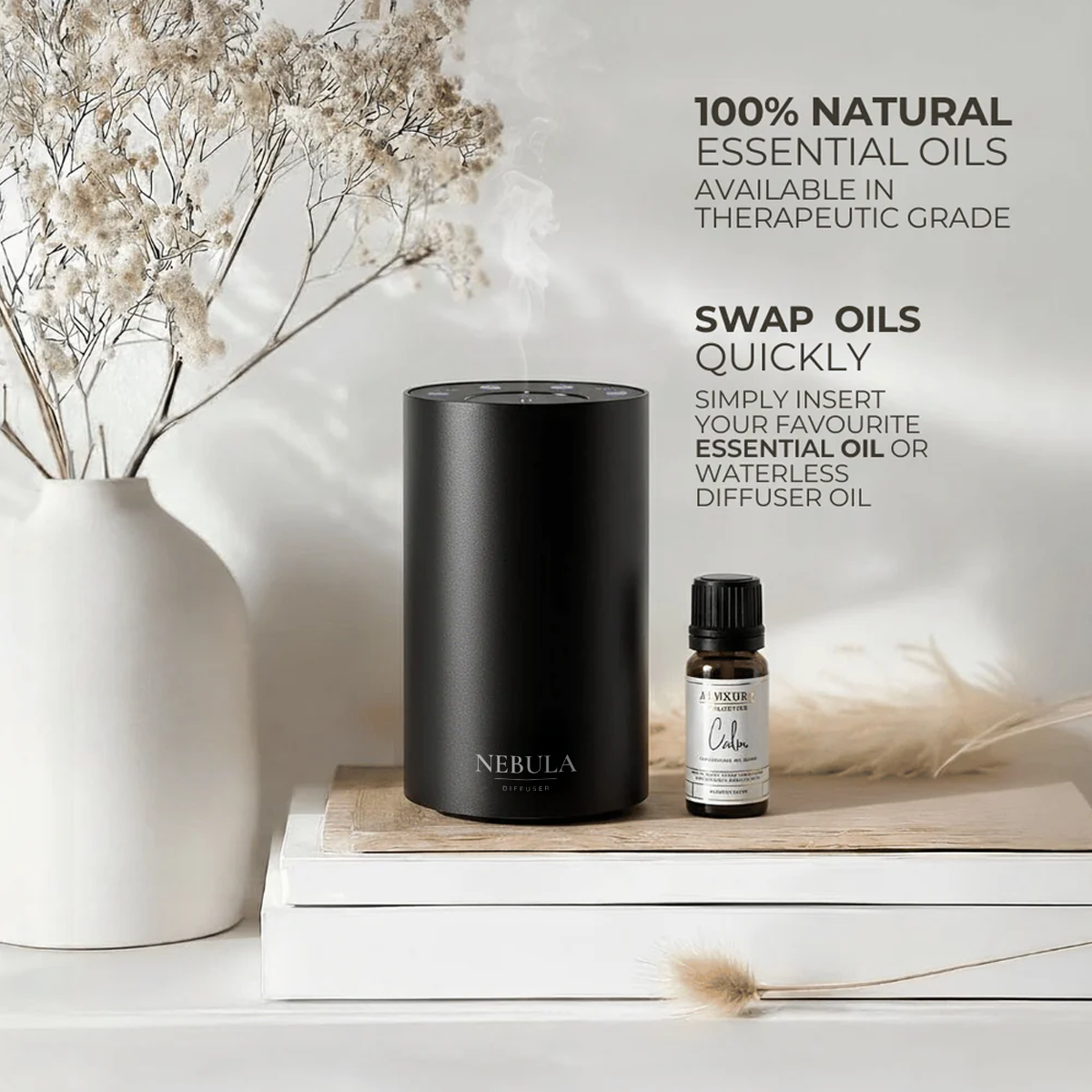 Black waterless diffuser and essential oil bottle on a wooden surface with decorative elements.