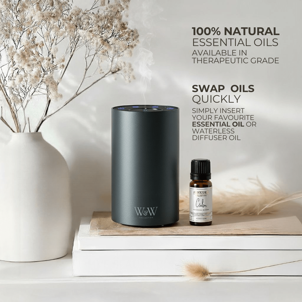 Grey waterless diffuser and essential oil bottle on a wooden surface with decorative elements.