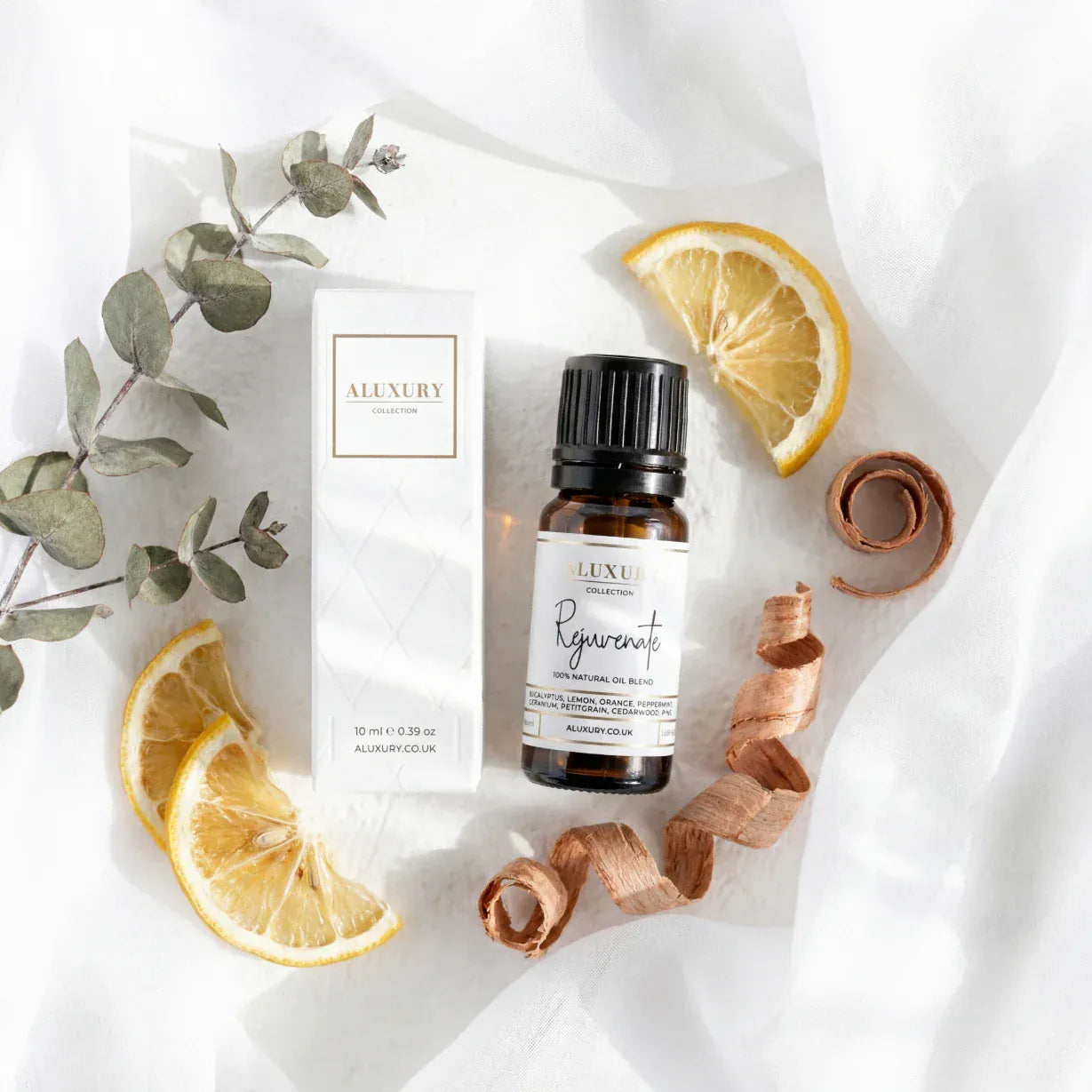 Aluxury essential oil bottle with packaging and lemon slices on a white background