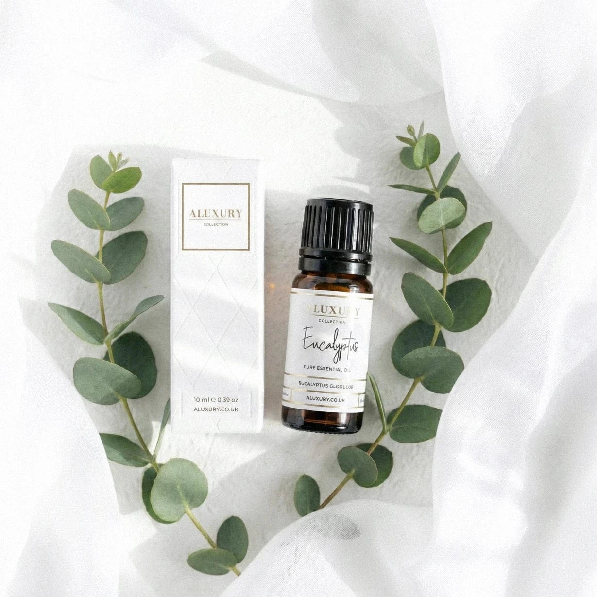 Aluxury eucalyptus essential oil bottle and packaging on a white fabric background