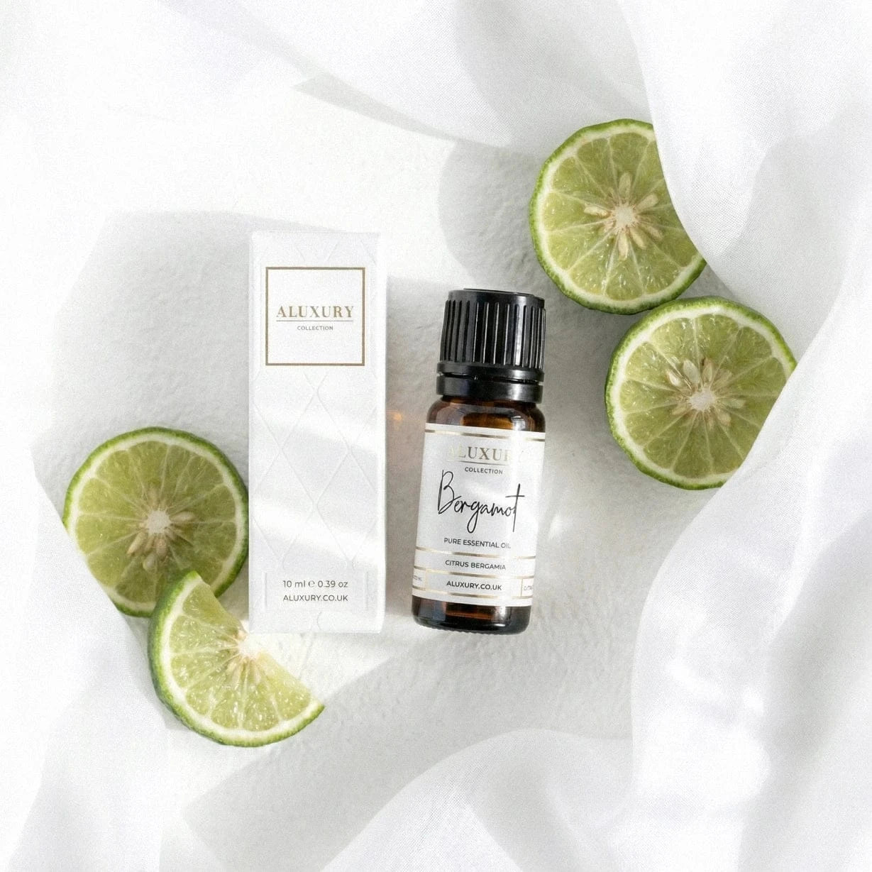 Aluxury Bergamot essential oil bottle and packaging on a white fabric background