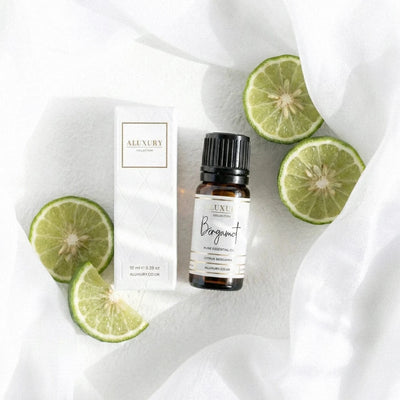 Aluxury Bergamot essential oil bottle and packaging on a white fabric background