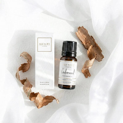 Cedarwood essential oil bottle and packaging on a white fabric background