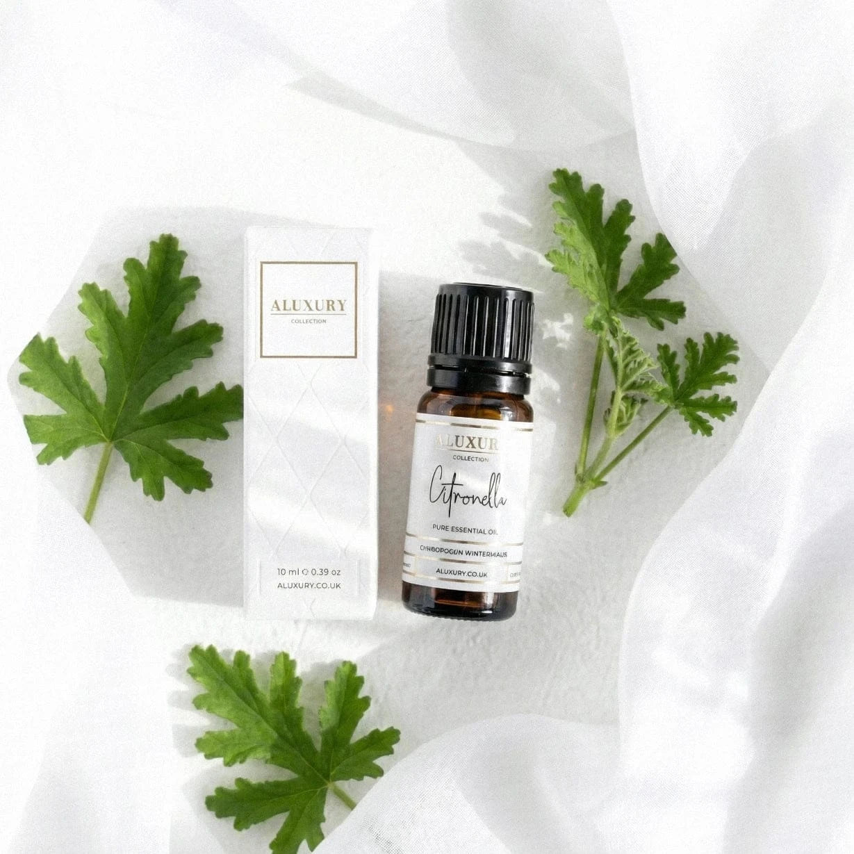 Citronella essential oil bottle and packaging on a white fabric background