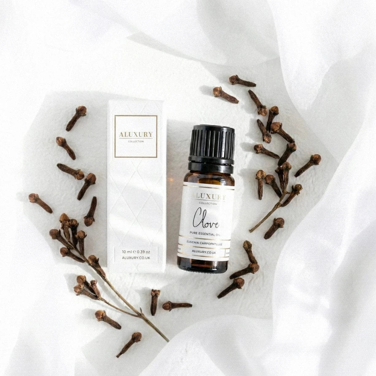 Aluxury Clove essential oil bottle and packaging on a white background with clove branches.