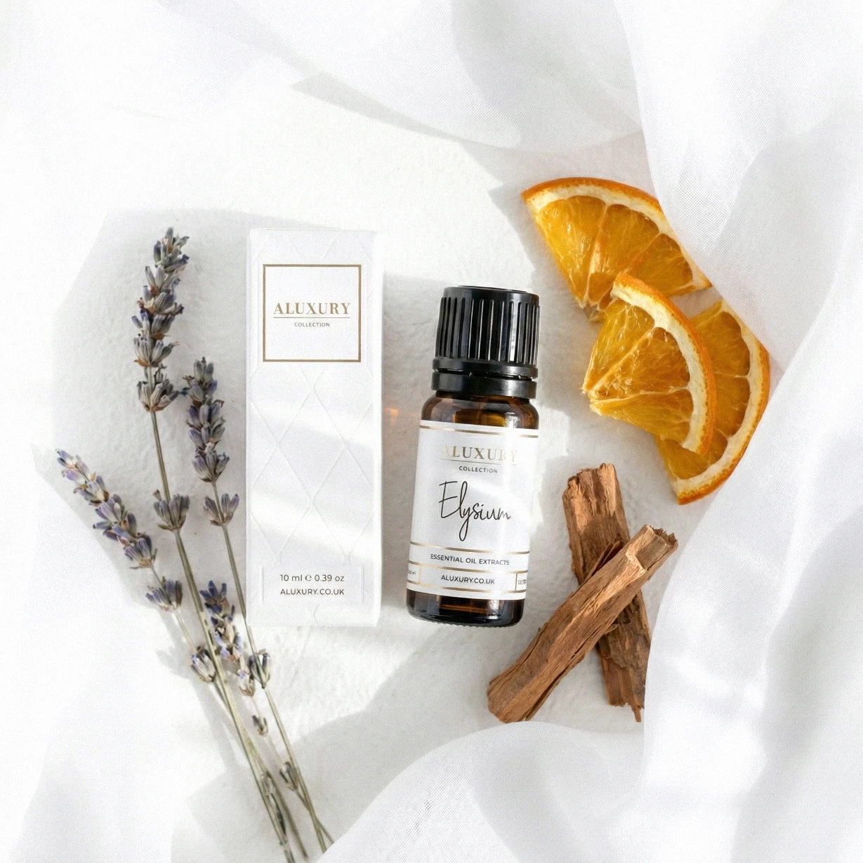 Aluxury essential oil bottle with packaging, lavender, orange slices, and sandalwood sticks on a white background
