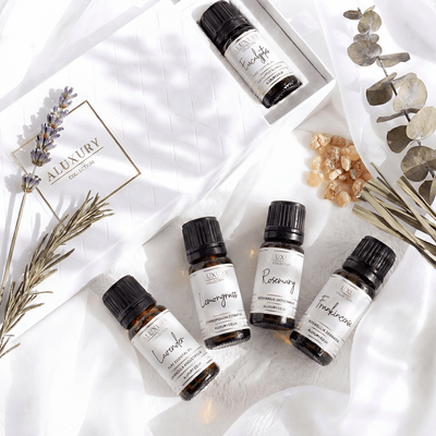Collection of essential oil bottles with labels on a white surface with herbs and crystals.