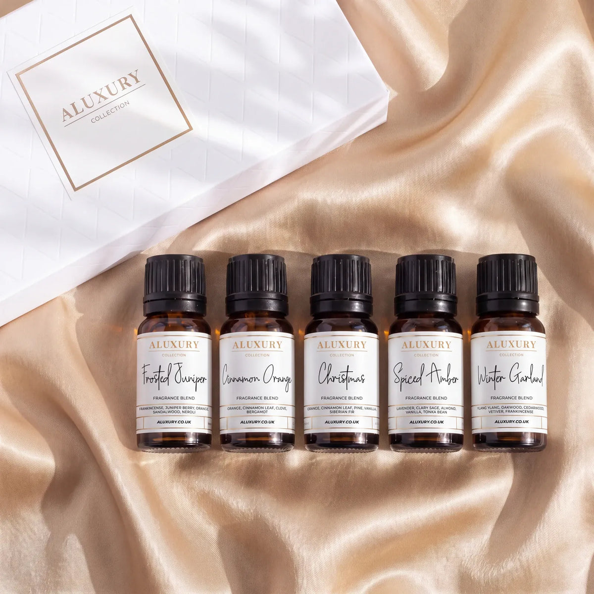 Festive Oils Gift Set on champagne gold silk with five 10ml diffuser oils: Frosted Juniper, Cinnamon Orange, Christmas, Spiced Amber and Winter Garland