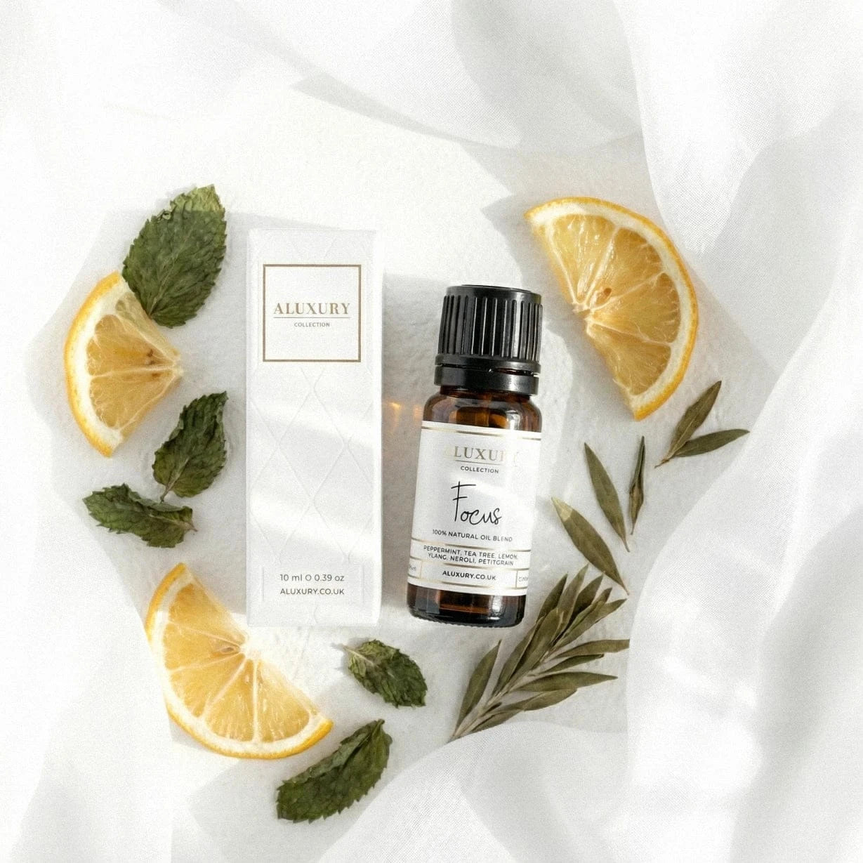 A bottle of 'Focus' essential oil with lemon slices and leaves on a white background