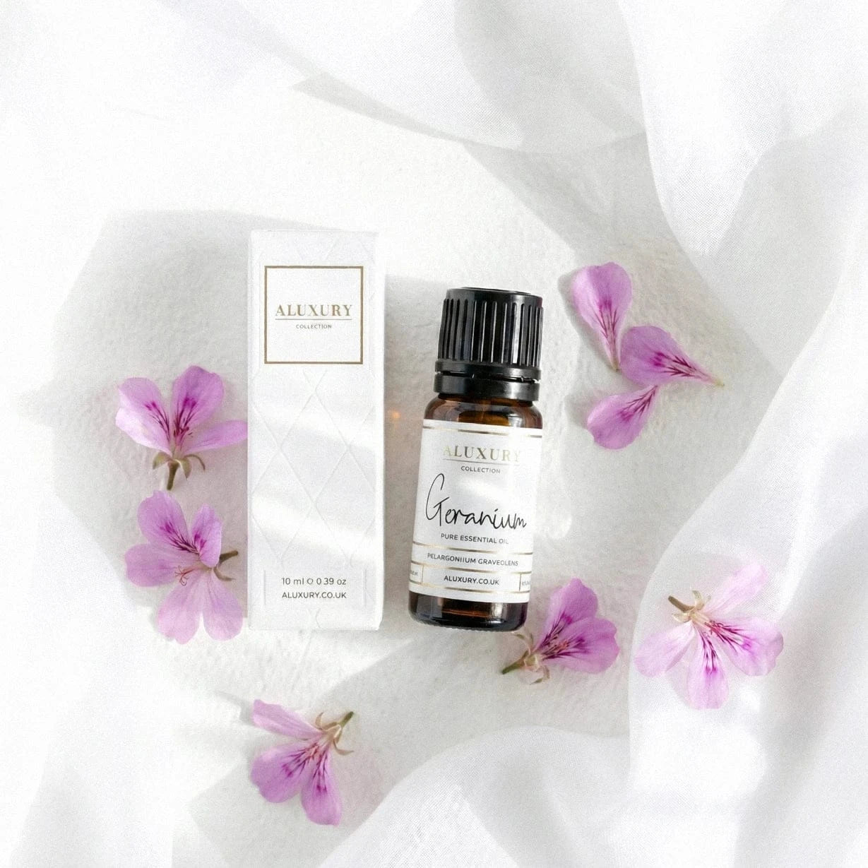 Aluxury geranium essential oil bottle and packaging on a white fabric background