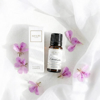 Aluxury geranium essential oil bottle and packaging on a white fabric background