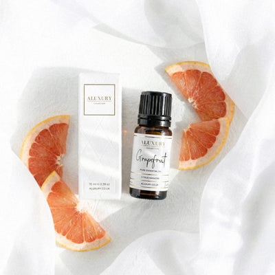 Aluxury grapefruit essential oil bottle and packaging on a white fabric background