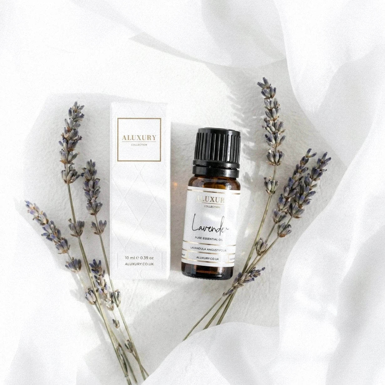 Aluxury lavender essential oil bottle and packaging on a white fabric background
