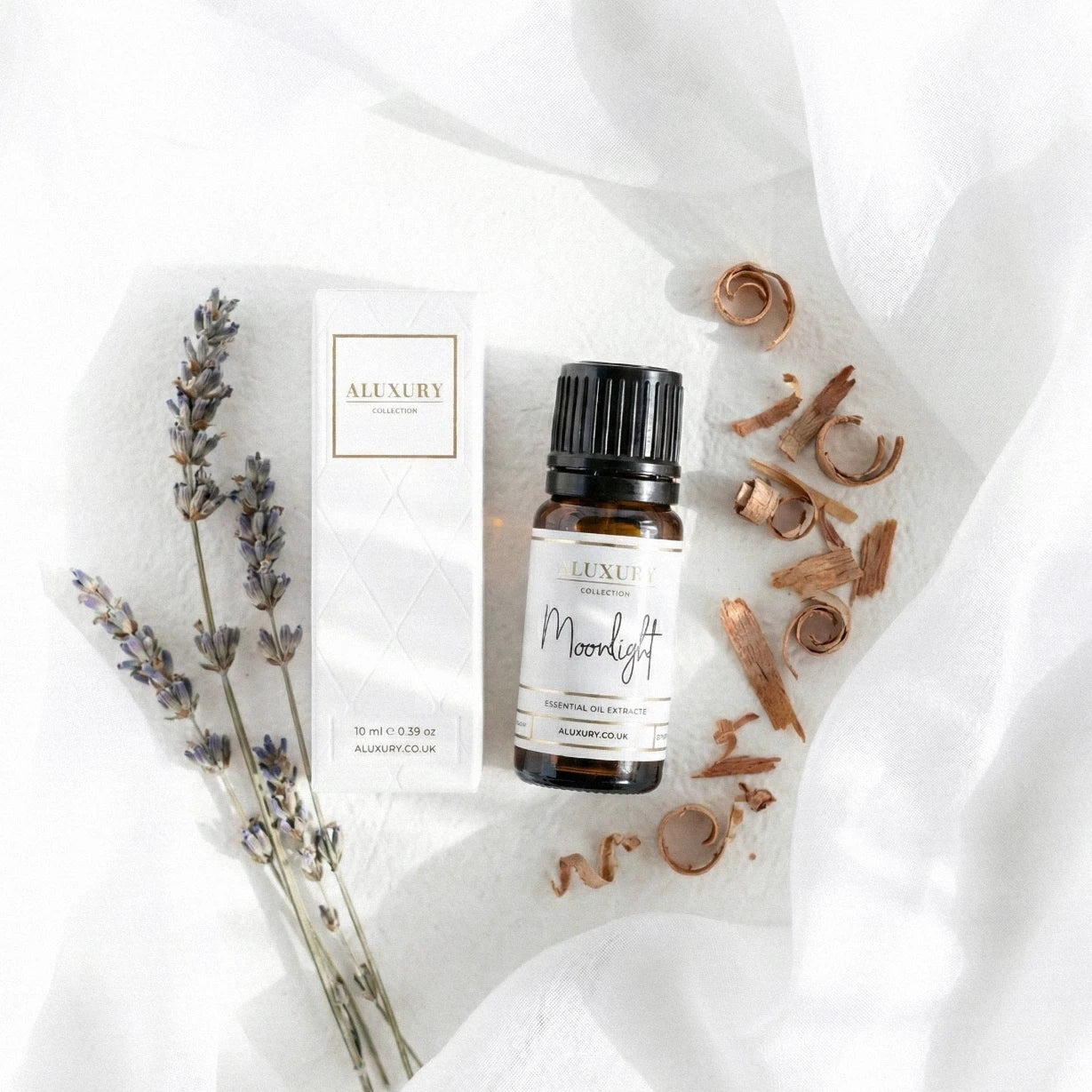 Aluxury essential oil bottle labeled 'Moonlight' with lavender and cinnamon on a white fabric background