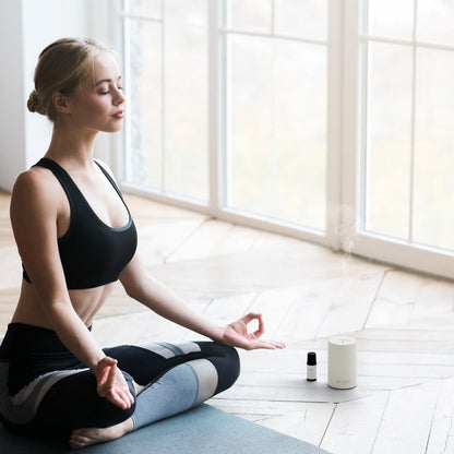 Woman meditating with Nebula waterless EO diffuser 