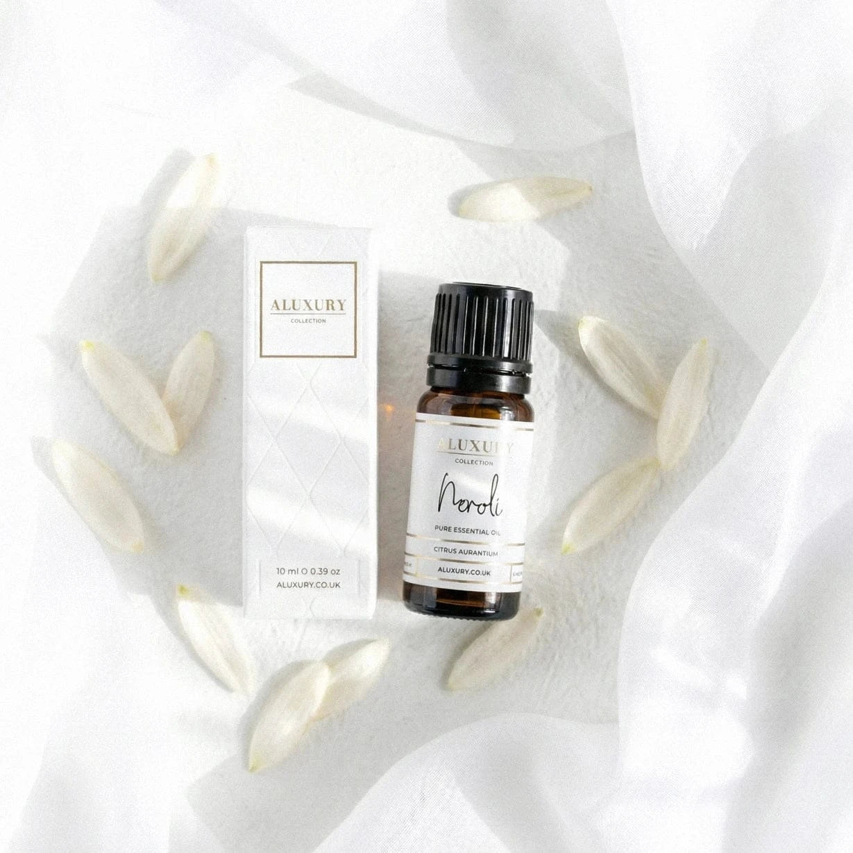 Neroli essential oil bottle and packaging on a white fabric background