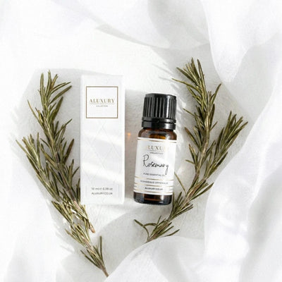 Bottle of Luxe Rosemary essential oil with packaging on a white fabric background