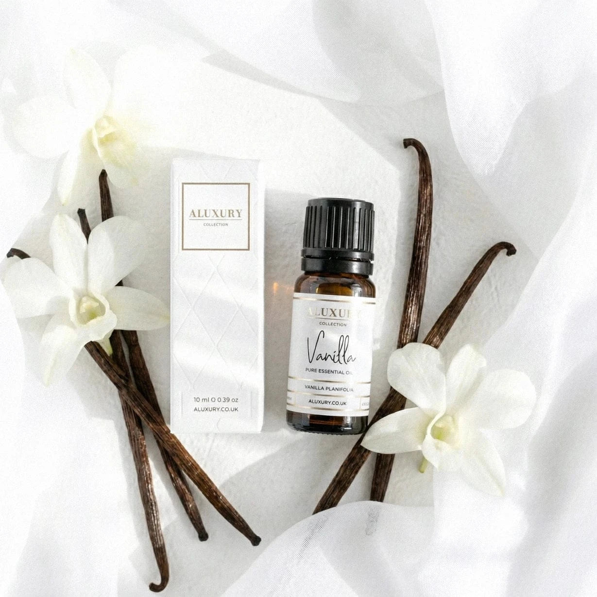 Aluxury vanilla essential oil bottle and packaging on a white fabric background
